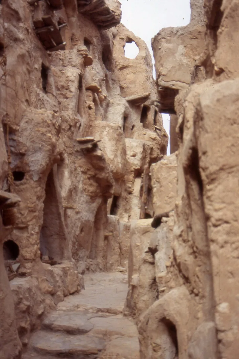 Narrow passage between weathered earthen and stone walls in the Nafusa Mountains